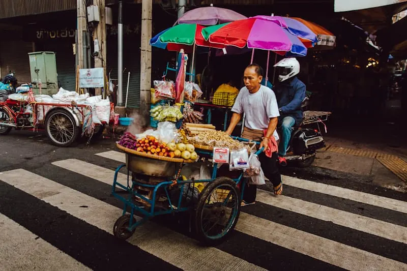 A man pushing a food cart along the street